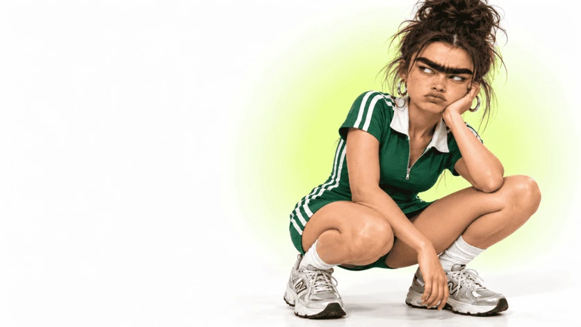Character in green outfit, exaggerated eyebrows and pensive expression