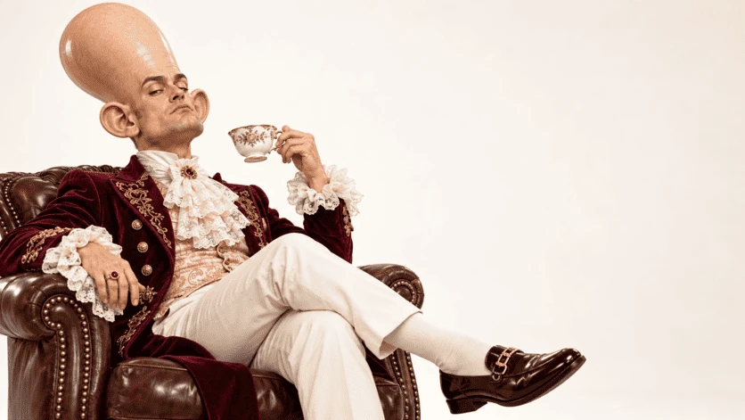 Character with an oversized skull having tea in a leather armchair