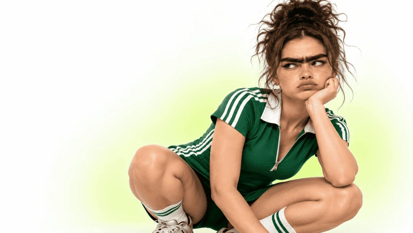 Character in green outfit and exaggerated eyebrows, pensive expression